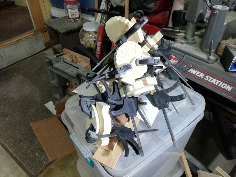 Wooden turkey bodies and wing pieces held together with clamps while the glue dries in the workshop.