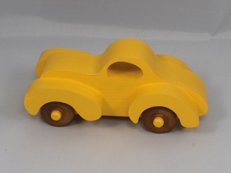 Handmade wooden toy car vintage style of a fat fendered coupe painted bright yellow with nonmarring amber shellac finished wheels. It is an excellent push toy for a younger child.