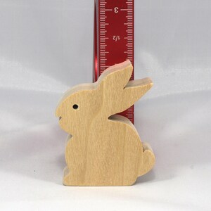 May include: A wooden rabbit figurine, standing approximately 3 inches tall, with a light brown color and a simple design.