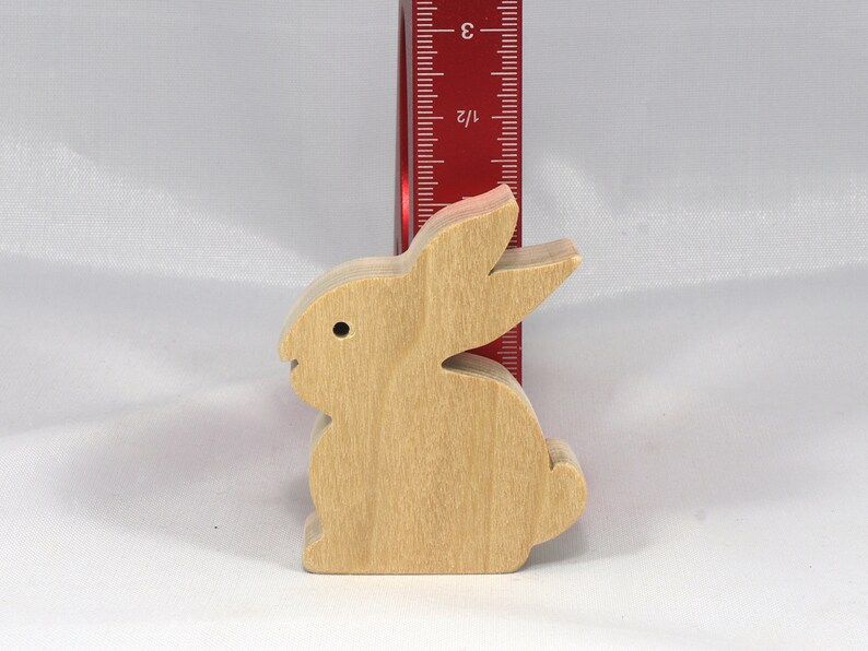 May include: A wooden rabbit figurine, standing approximately 3 inches tall, with a light brown color and a simple design.
