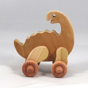 Handmade wooden push toy dinosaur made from select grade hardwoods and finished with a non-toxic coating.