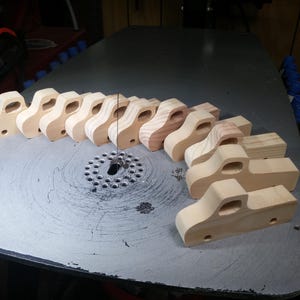 Handmade wooden toy pickup truck bodies lined up on a scroll saw table during production in my woodworking shop.