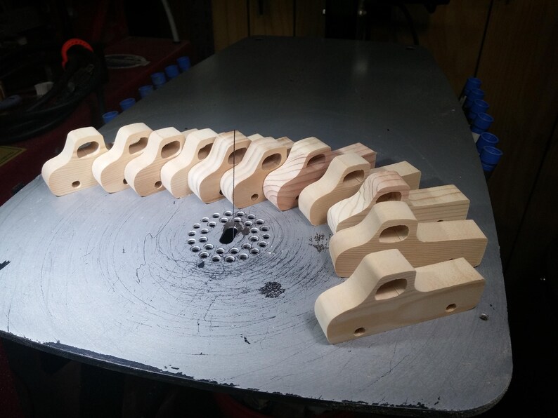 Handmade wooden toy pickup truck bodies lined up on a scroll saw table during production in my woodworking shop.