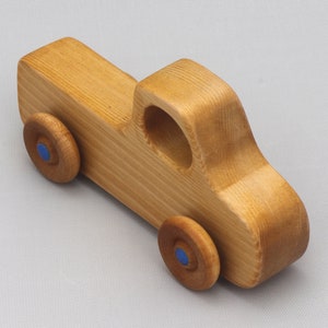 Wooden toy pickup truck from the Play Pal Collection at Odin's Toy Factory. Made from natural wood, finished with amber shellac, and accented with metallic sapphire blue acrylic paint on the wheel hubs. Made In The USA. Approximate dimensions: length 3-1/2 inches, height 1-3/8 inches, width 1-1/2 inches, wheels 3/4 inch diameter. Handmade in Tallahassee, Florida. Natural wood grain and color variations.