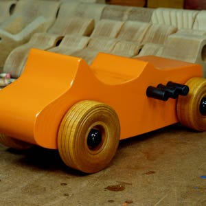 Handmade wooden toy car modeled after a 1927 T-Bucket hot rod. Finished with orange and black acrylic paint and amber shellac.