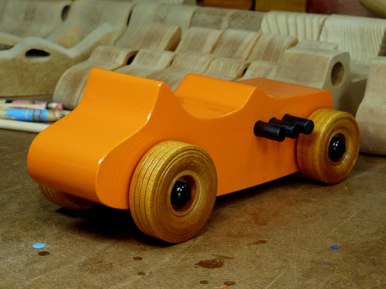 Handmade wooden toy car modeled after a 1927 T-Bucket hot rod. Finished with orange and black acrylic paint and amber shellac.