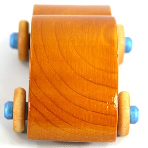 A handmade wooden toy car modeled after the iconic 1957 bug, finished with amber shellac and metallic sapphire blue trim. It's part of my Play Pal Collection.