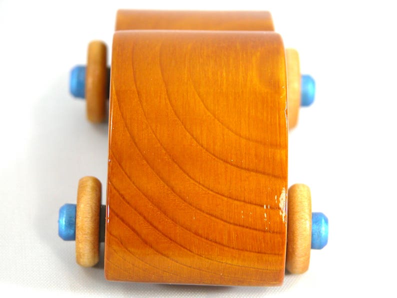 A handmade wooden toy car modeled after the iconic 1957 bug, finished with amber shellac and metallic sapphire blue trim. It's part of my Play Pal Collection.