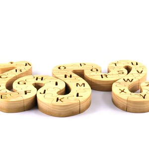 Hand-cut Alphabet Snake Puzzle made from premium hardwood, finished with mineral oil and beeswax for durability. Each of the 26 pieces represents a letter, promoting alphabet learning and essential skills development in kids through play.