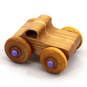 May include: A handcrafted wooden toy car with a natural wood grain finish. The car features four wooden wheels with purple center accents. The body of the car has a rounded design with a small opening. A classic toy for children.