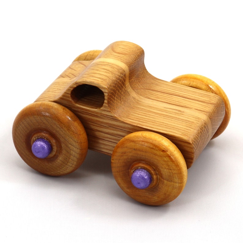 May include: A handcrafted wooden toy car with a natural wood grain finish. The car features four wooden wheels with purple center accents. The body of the car has a rounded design with a small opening. A classic toy for children.