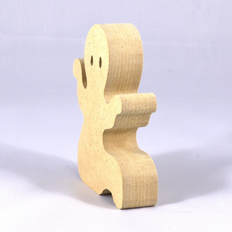 A handmade, unpainted wooden ghost cutout stands upright on a white background. The light-colored solid wood figure has a rounded head with two circular eye cutouts, raised wavy arms, and a curved wavy base, ready for painting or crafting.