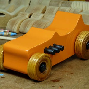 Handmade wooden toy car modeled after a 1927 T-Bucket hot rod. Finished with orange and black acrylic paint and amber shellac.