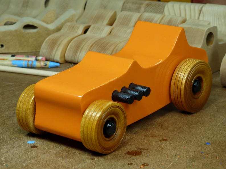 Handmade wooden toy car modeled after a 1927 T-Bucket hot rod. Finished with orange and black acrylic paint and amber shellac.