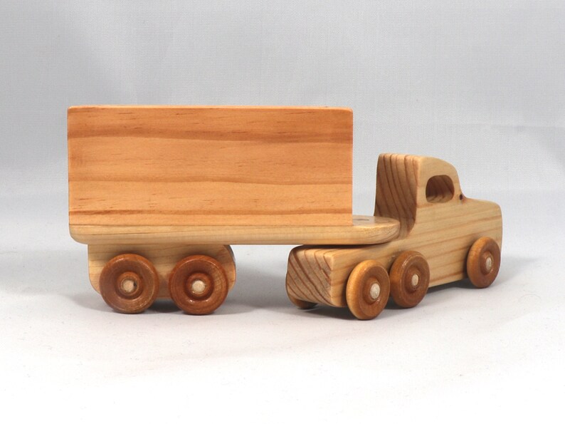 Handmade wooden toy tractor trailer semi truck finished with clear shellac. Crafted from natural wood using traditional woodworking tools. Approximate size 7 inches long. Made in Tallahassee, Florida, USA from Odin's Toy Factory Play Pal Collection.