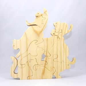 Handmade wooden puzzle featuring several cat-shaped pieces stacked on top of each other in various playful poses, forming a balanced tower. The cats are crafted with smooth edges and natural wood tones, highlighting their unique shapes and expressions.