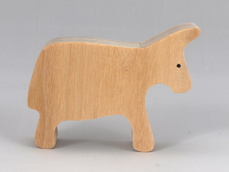 A handmade and unfinished wooden toy cow cutout is perfect for those who love to paint and customize their toys. It is freestanding and stackable, making it a versatile addition to any playroom or nursery. From My Itty Bitty Animal Collection.