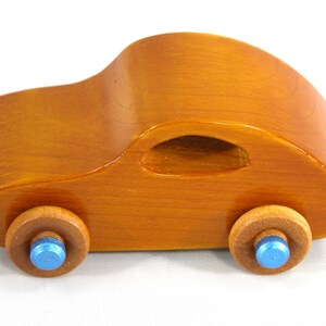 A handmade wooden toy car modeled after the iconic 1957 bug, finished with amber shellac and metallic sapphire blue trim. It's part of my Play Pal Collection.