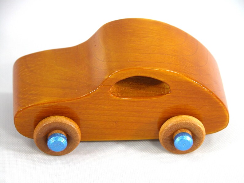 A handmade wooden toy car modeled after the iconic 1957 bug, finished with amber shellac and metallic sapphire blue trim. It's part of my Play Pal Collection.