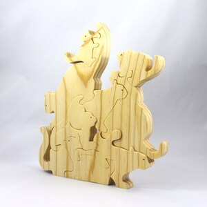 Handmade wooden puzzle featuring several cat-shaped pieces stacked on top of each other in various playful poses, forming a balanced tower. The cats are crafted with smooth edges and natural wood tones, highlighting their unique shapes and expressions.