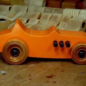 Handmade wooden toy car modeled after a 1927 T-Bucket hot rod. Finished with orange and black acrylic paint and amber shellac.