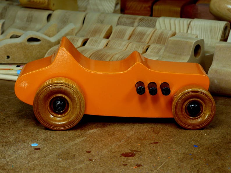 Handmade wooden toy car modeled after a 1927 T-Bucket hot rod. Finished with orange and black acrylic paint and amber shellac.