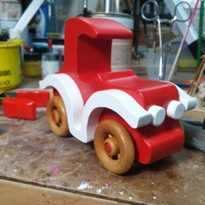 Handmade wooden toy car, vintage style red Model T Coupe by Odin's Toy Factory. Two-tone red and white acrylic paint with spoked wooden wheels finished in amber shellac. Approximate dimensions: 5 inches long, 4 inches high, 2.5 inches wide. Part of Bad Bob’s Custom Motors Collection. Crafted from natural wood using traditional woodworking tools. Handmade in Tallahassee, Florida, USA.