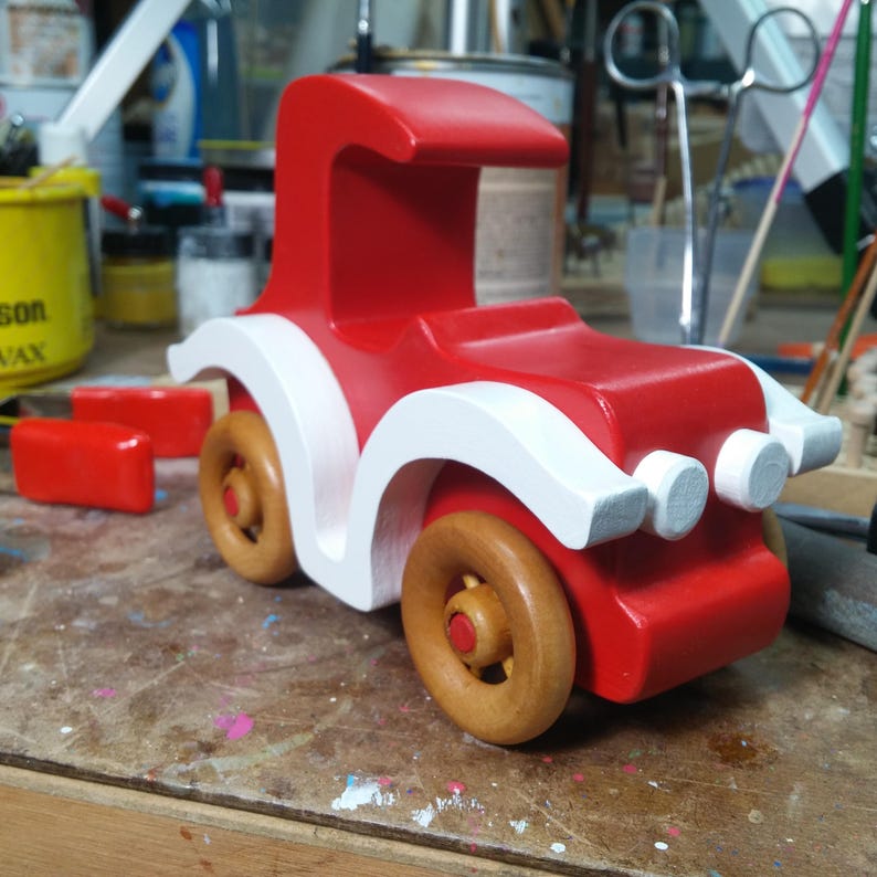 Handmade wooden toy car, vintage style red Model T Coupe by Odin's Toy Factory. Two-tone red and white acrylic paint with spoked wooden wheels finished in amber shellac. Approximate dimensions: 5 inches long, 4 inches high, 2.5 inches wide. Part of Bad Bob’s Custom Motors Collection. Crafted from natural wood using traditional woodworking tools. Handmade in Tallahassee, Florida, USA.