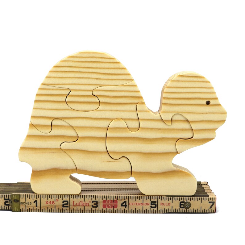 Handmade wooden turtle puzzle with 5 simple interlocking pieces. Freestanding 5-piece wooden puzzle. Approximate dimensions: 5 inches high by 7.25 inches long by 0.75 inches thick. Finished with mineral oil and beeswax blend. Handcrafted in Tallahassee, Florida, USA, using natural wood. Unique wood grain color and knot variations. Odin’s Toy Factory.