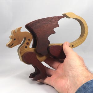 Handmade wood dragon figurine made from select grade contrasting hardwoods and hand-finished with a custom mixture of mineral oil and waxes. Displayed in the makers hand for scale.