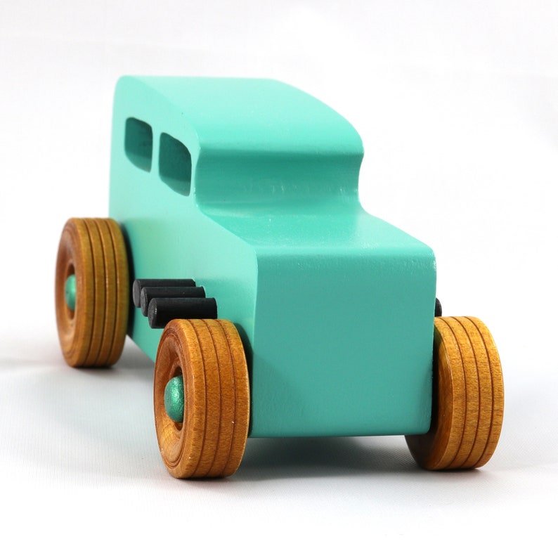 Handmade wooden toy car, 1932 Hot Rod Sedan, painted turquoise with metallic green and black trim. The wheels are finished with nonmarring amber shellac. Handcrafted from natural wood in Tallahassee, Florida, USA. Approximate size: 6 inches long, 3 inches high, 2.5 inches wide. Odin's Toy Factory custom wooden toy.