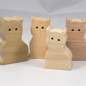 May include: Four wooden cat figurines, each with a different wood grain pattern. The cats are all facing forward with their ears perked up.