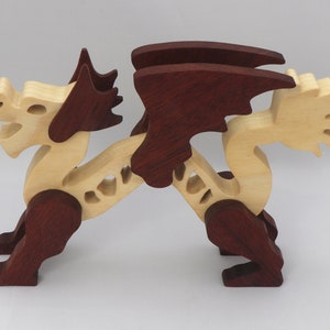 Handmade wooden dragon figurine. crafted from contrasting hardwoods with a light natural wood body and head paired with rich dark reddish-brown wings, legs, and horns.