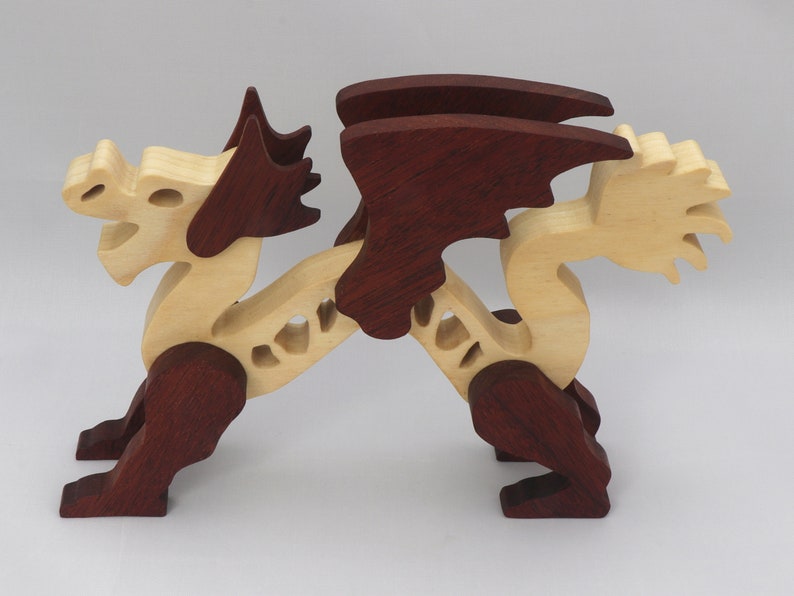 Handmade wooden dragon figurine. crafted from contrasting hardwoods with a light natural wood body and head paired with rich dark reddish-brown wings, legs, and horns.