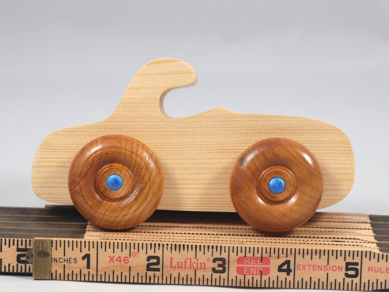 Handmade wooden toy car. The body is finished with clear shellac, and the wheels are finished with amber shellac. The hubs are painted with metallic sapphire blue trim.