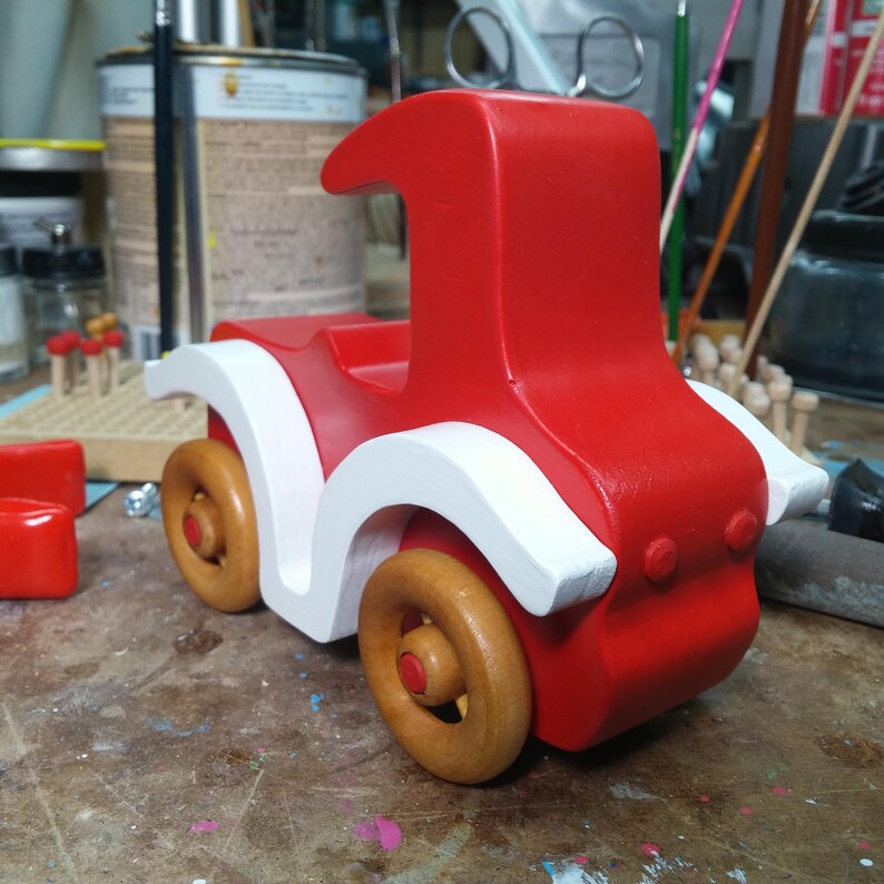 Handmade wooden toy car, vintage style red Model T Coupe by Odin's Toy Factory. Two-tone red and white acrylic paint with spoked wooden wheels finished in amber shellac. Approximate dimensions: 5 inches long, 4 inches high, 2.5 inches wide. Part of Bad Bob’s Custom Motors Collection. Crafted from natural wood using traditional woodworking tools. Handmade in Tallahassee, Florida, USA.