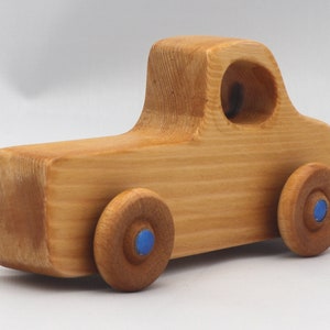 Wooden toy pickup truck from the Play Pal Collection at Odin's Toy Factory. Made from natural wood, finished with amber shellac, and accented with metallic sapphire blue acrylic paint on the wheel hubs. Made In The USA. Approximate dimensions: length 3-1/2 inches, height 1-3/8 inches, width 1-1/2 inches, wheels 3/4 inch diameter. Handmade in Tallahassee, Florida. Natural wood grain and color variations.