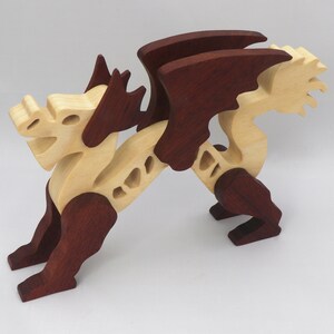 Handmade wooden dragon figurine. crafted from contrasting hardwoods with a light natural wood body and head paired with rich dark reddish-brown wings, legs, and horns.