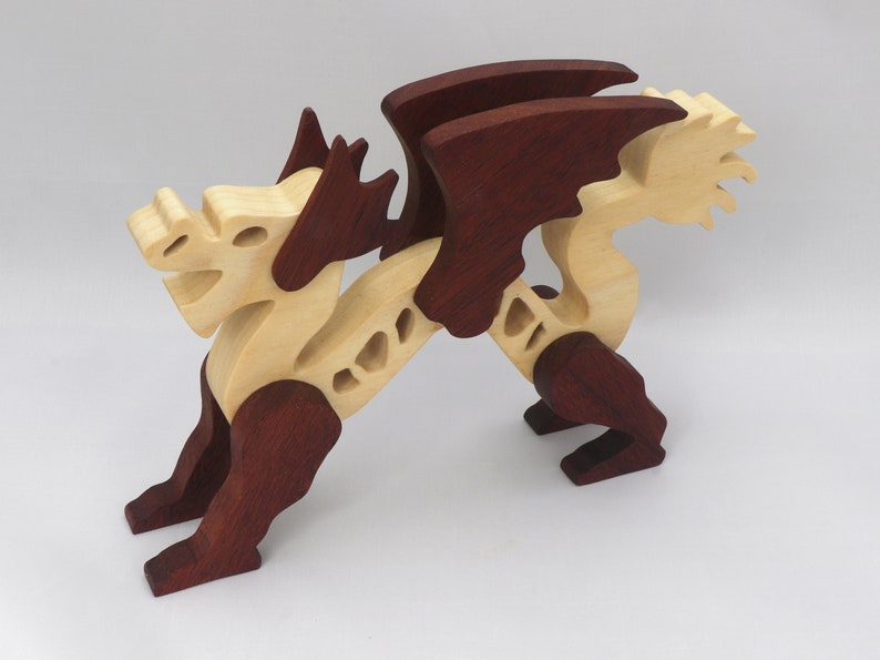 Handmade wooden dragon figurine. crafted from contrasting hardwoods with a light natural wood body and head paired with rich dark reddish-brown wings, legs, and horns.