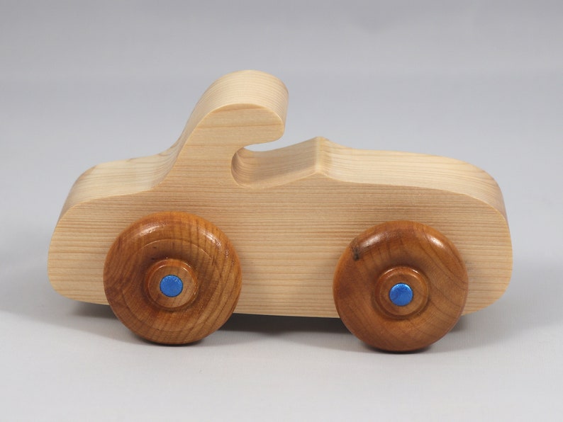 Handmade wooden toy car. The body is finished with clear shellac, and the wheels are finished with amber shellac. The hubs are painted with metallic sapphire blue trim.