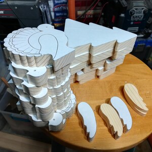 Stacks of freshly cut wooden turkey bodies and separate wing pieces with paper patterns attached in the workshop.