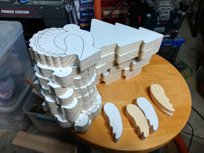 Stacks of freshly cut wooden turkey bodies and separate wing pieces with paper patterns attached in the workshop.