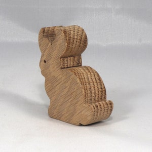 May include: A wooden rabbit figurine with a brown finish. The rabbit is standing on its hind legs with its ears up.