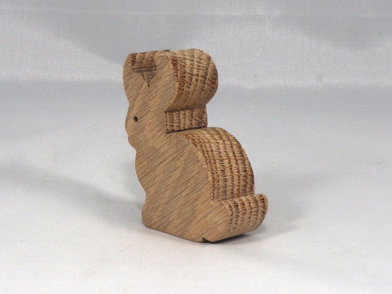 May include: A wooden rabbit figurine with a brown finish. The rabbit is standing on its hind legs with its ears up.