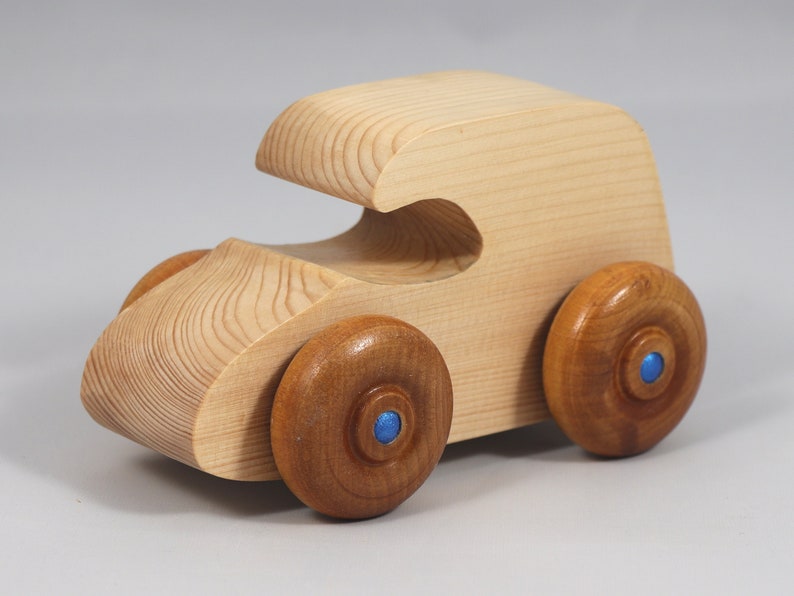 Handmade wooden toy car. The body is finished with clear shellac, and the wheels are finished with amber shellac. The hubs are painted with metallic sapphire blue trim.