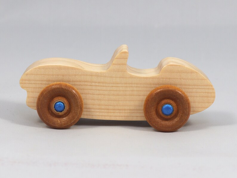 Handmade wooden toy car convertible sports coupe with a nontoxic satin polyethylene finish, amber shellac wheels, and metallic sapphire blue trim.