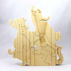 Handmade wooden puzzle featuring several cat-shaped pieces stacked on top of each other in various playful poses, forming a balanced tower. The cats are crafted with smooth edges and natural wood tones, highlighting their unique shapes and expressions.