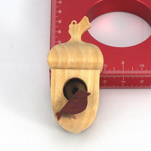Handmade wooden miniature birdhouse ornament cut from wood with rounded edges, natural wood grain and color variations, finished with non-toxic shellac or food-safe oils and beeswax, lightweight and ready to hang. Made in Tallahassee, Florida, USA, by Odin's Toy Factory.