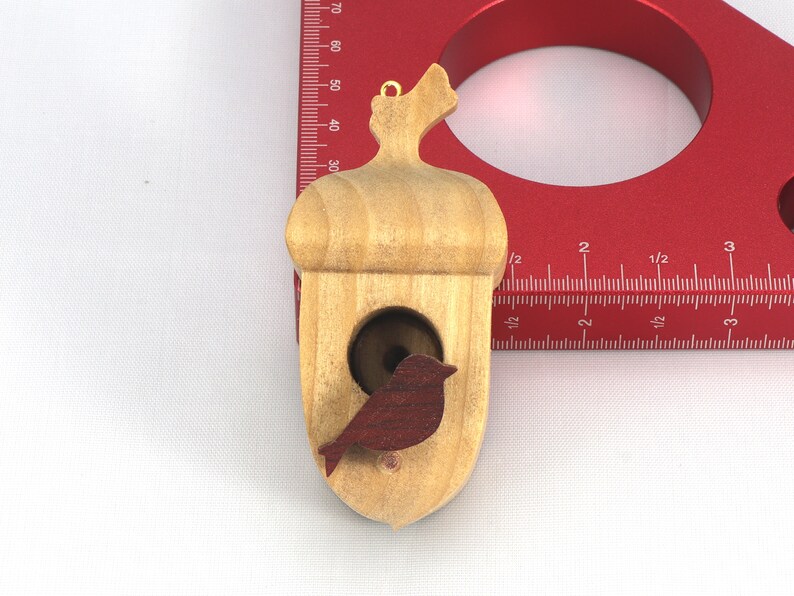 Handmade wooden miniature birdhouse ornament cut from wood with rounded edges, natural wood grain and color variations, finished with non-toxic shellac or food-safe oils and beeswax, lightweight and ready to hang. Made in Tallahassee, Florida, USA, by Odin's Toy Factory.