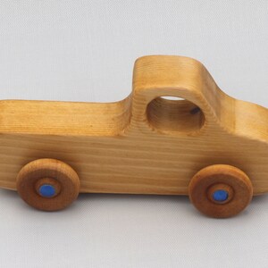 Wooden toy pickup truck from the Play Pal Collection at Odin's Toy Factory. Made from natural wood, finished with amber shellac, and accented with metallic sapphire blue acrylic paint on the wheel hubs. Made In The USA. Approximate dimensions: length 3-1/2 inches, height 1-3/8 inches, width 1-1/2 inches, wheels 3/4 inch diameter. Handmade in Tallahassee, Florida. Natural wood grain and color variations.